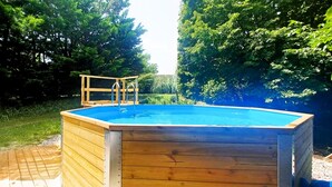 Una piscina elevada de madera con cubierta de madera y escaleras de metal.