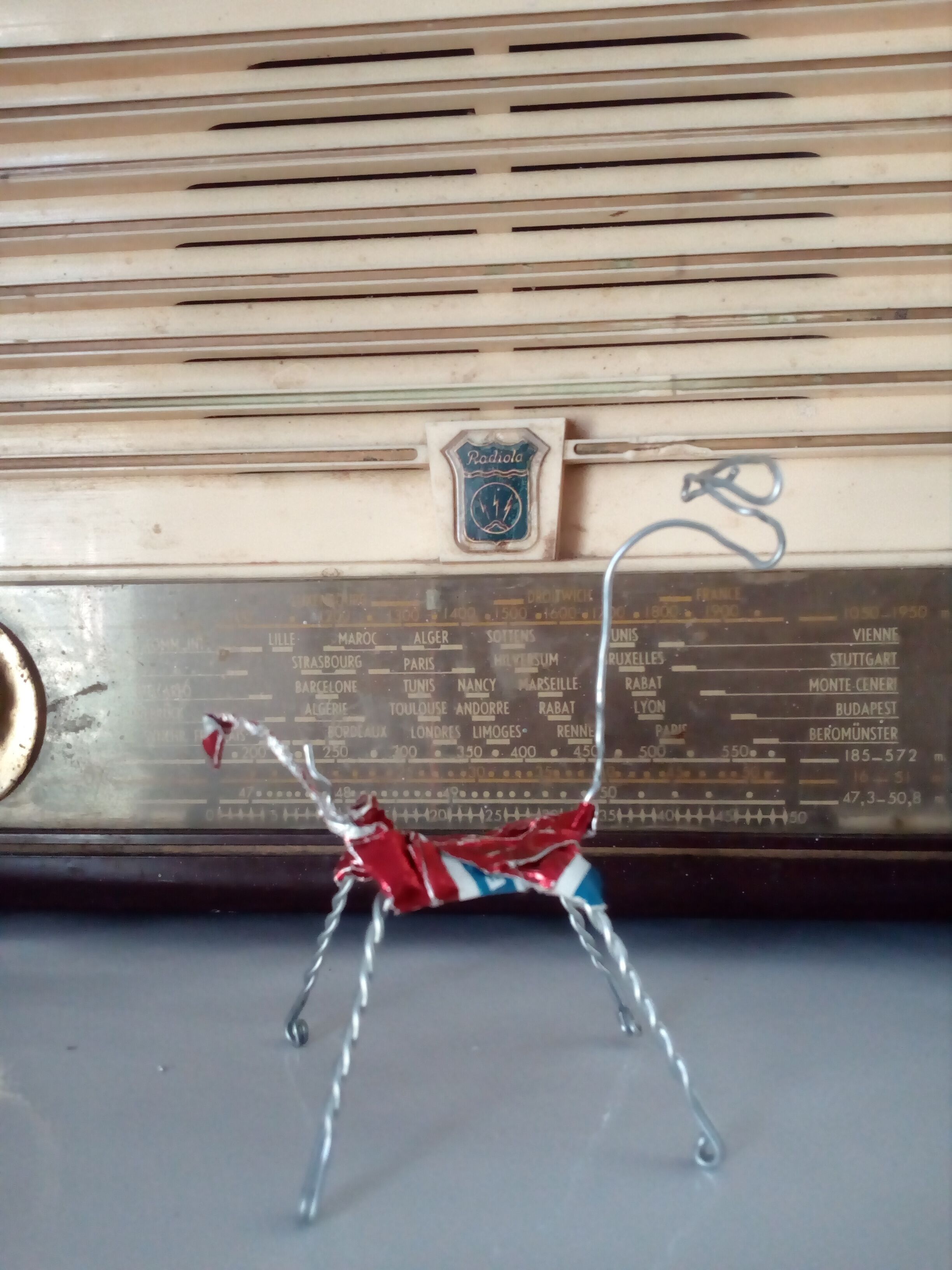 A vintage radio with a decorative metal figure in front of it.
