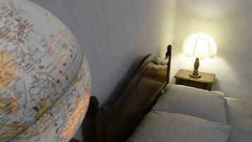 A bed with a wooden headboard, a globe, and a bedside table with a lamp.