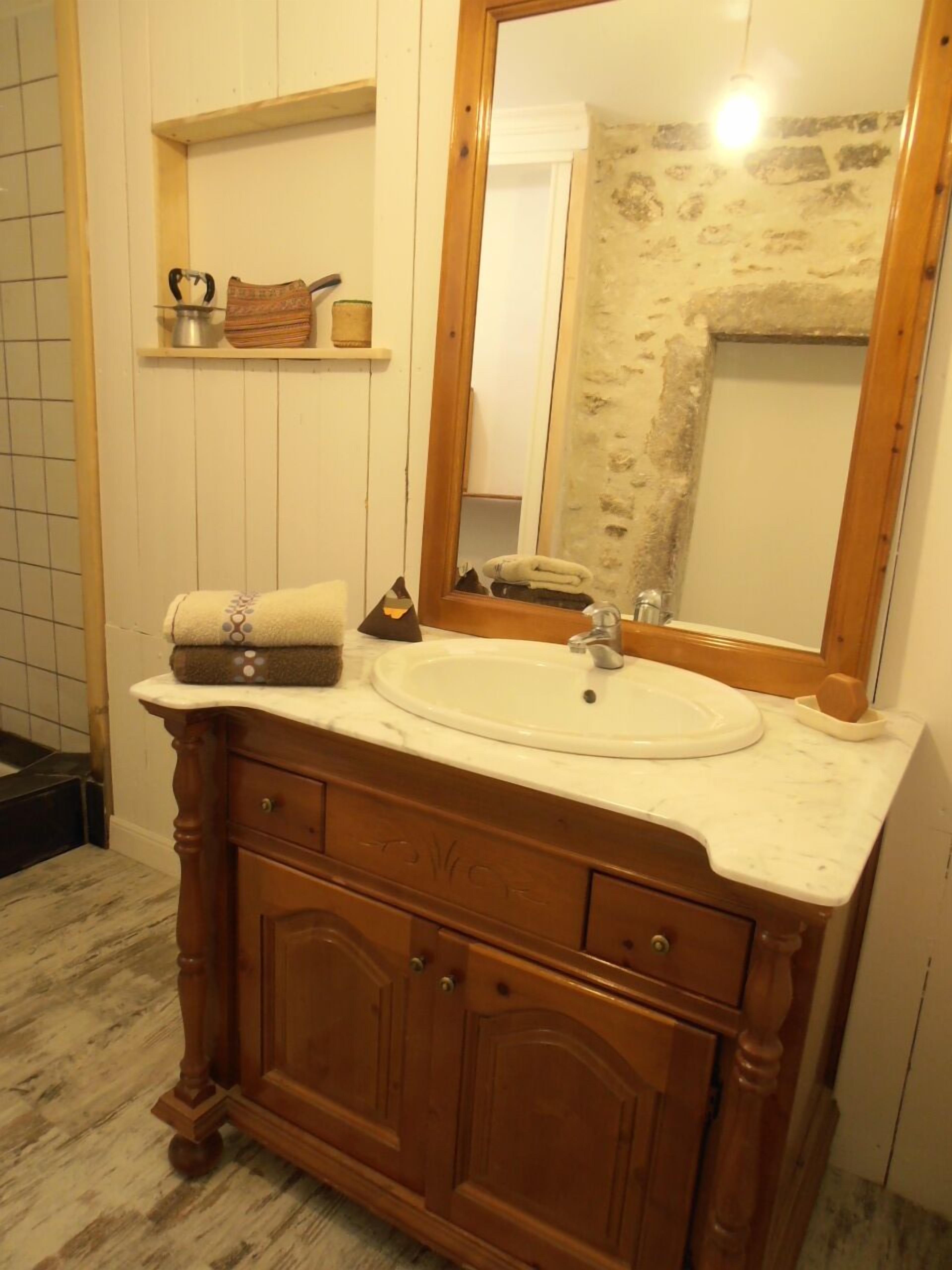 A wooden vanity with a marble countertop, a sink, and a mirror.