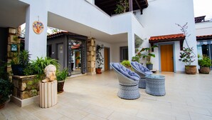 Un patio con sillones de mimbre, plantas en macetas y un busto de piedra.