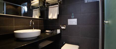 Un baño moderno con lavamanos blanco, espejo, toallero y retrete.