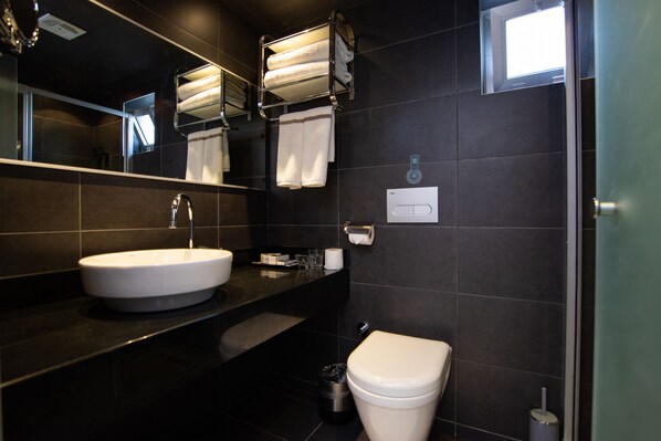 Un baño moderno con lavamanos blanco, espejo, toallero y retrete.