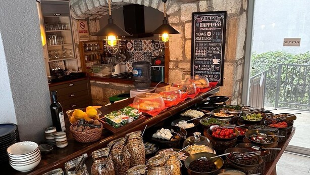 Montaje de bufé con diferentes alimentos y condimentos, un letrero con temática de los Beatles y vistas al exterior.