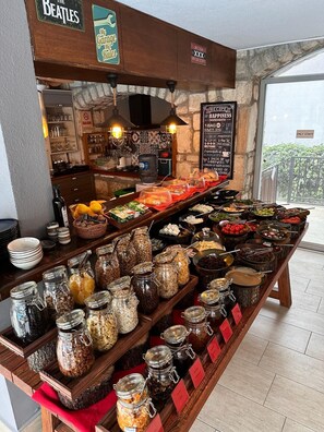 A buffet setup with various food items and condiments, a Beatles-themed sign, and a view of the outdoors. - Hotel Pier Marina Bodrum (Bodrum)
