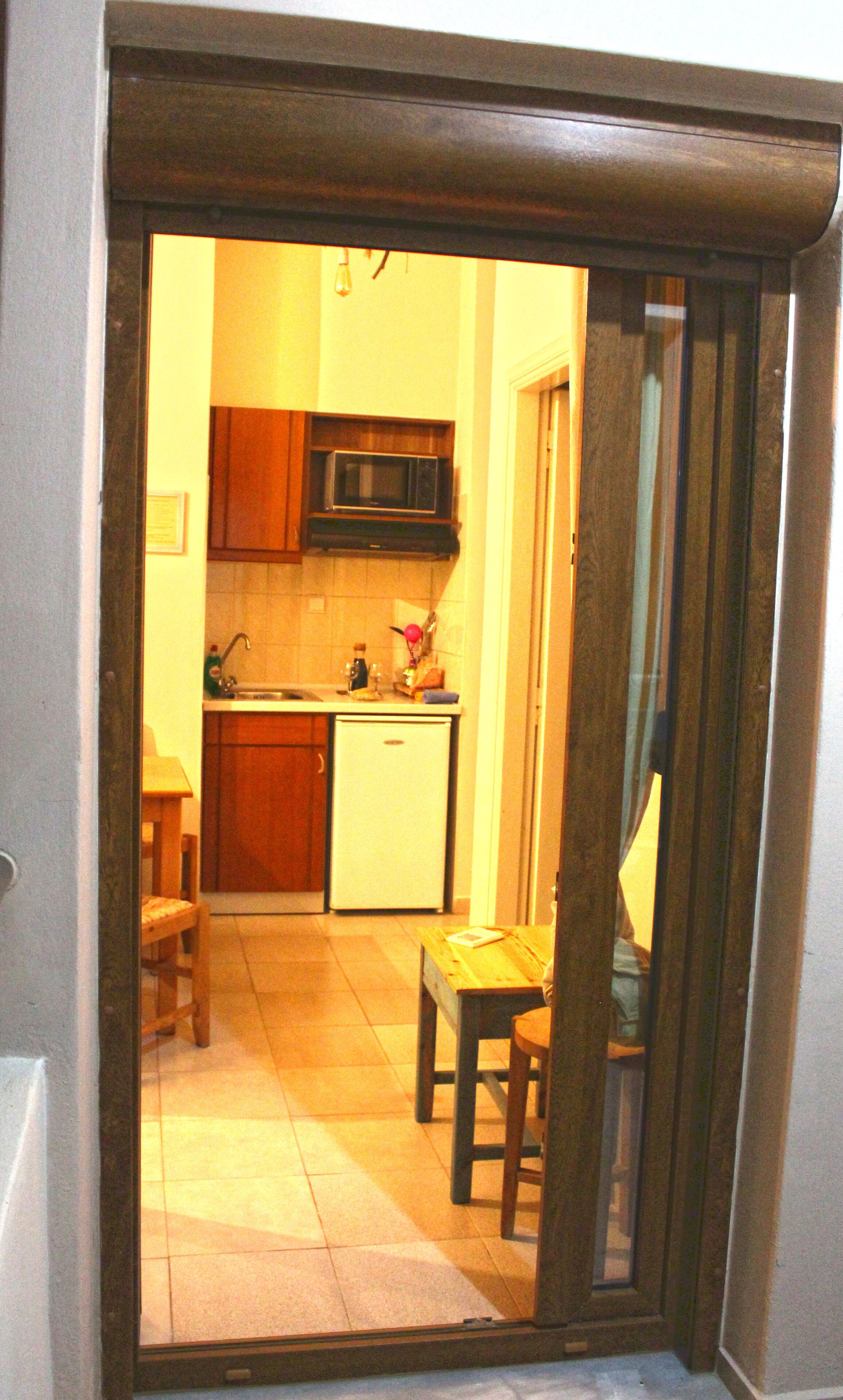 A kitchen with wooden cabinets, a microwave, a sink, and a small refrigerator.