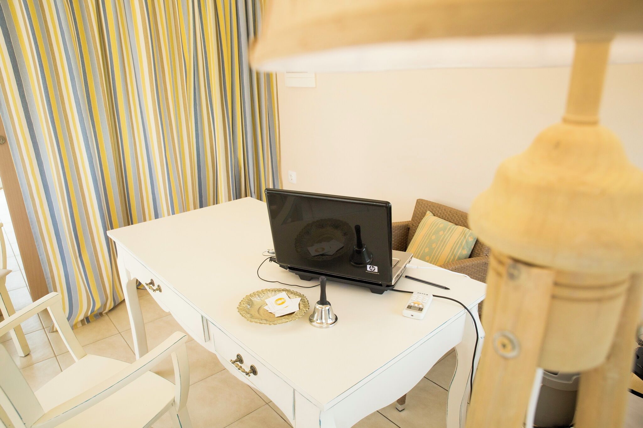 Ein weißer Schreibtisch mit einem Laptop, einer Lampe und einem Teller mit einer Karte.