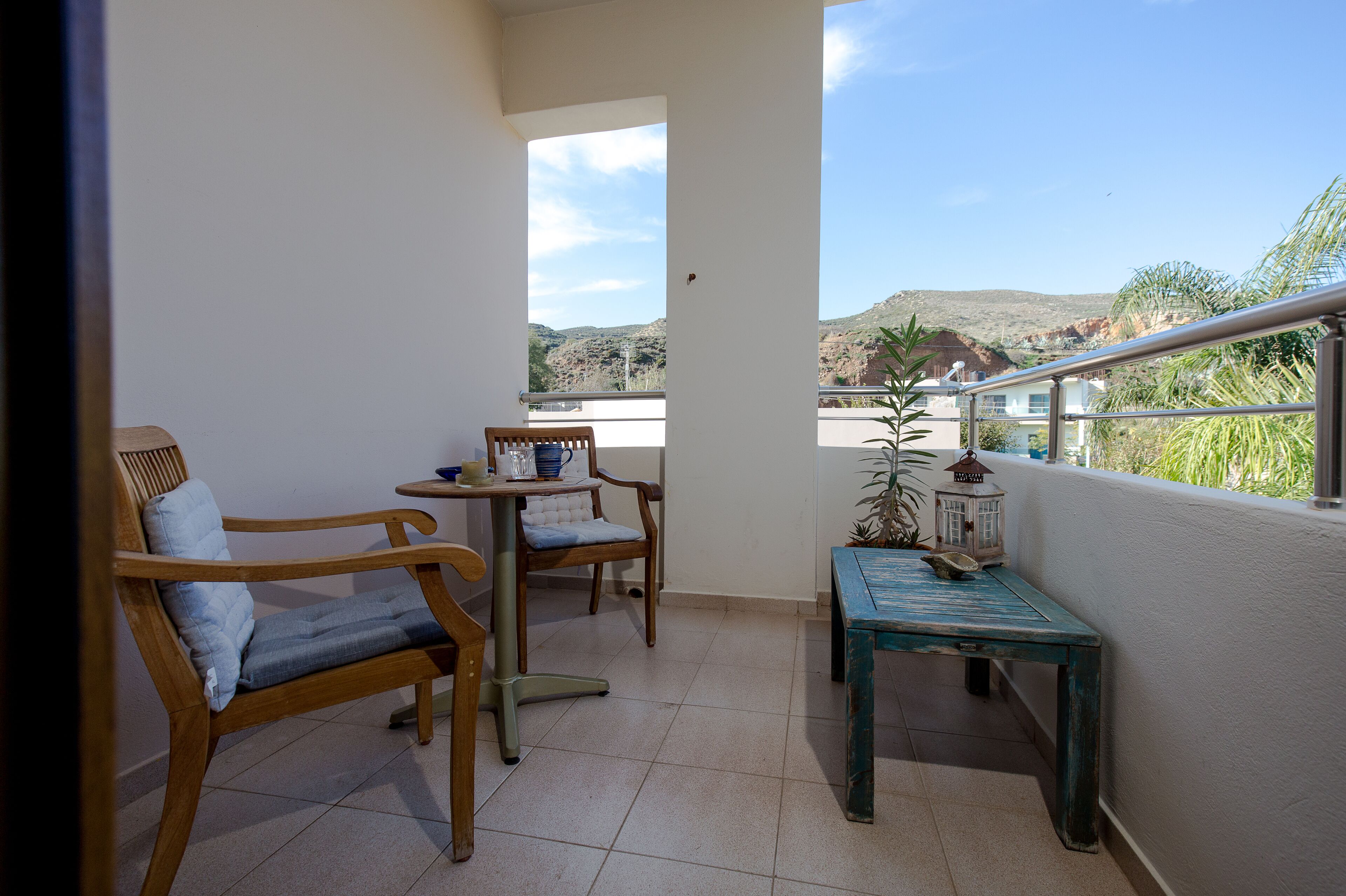 A balcony with a wooden chair, a small table, and a potted plant.