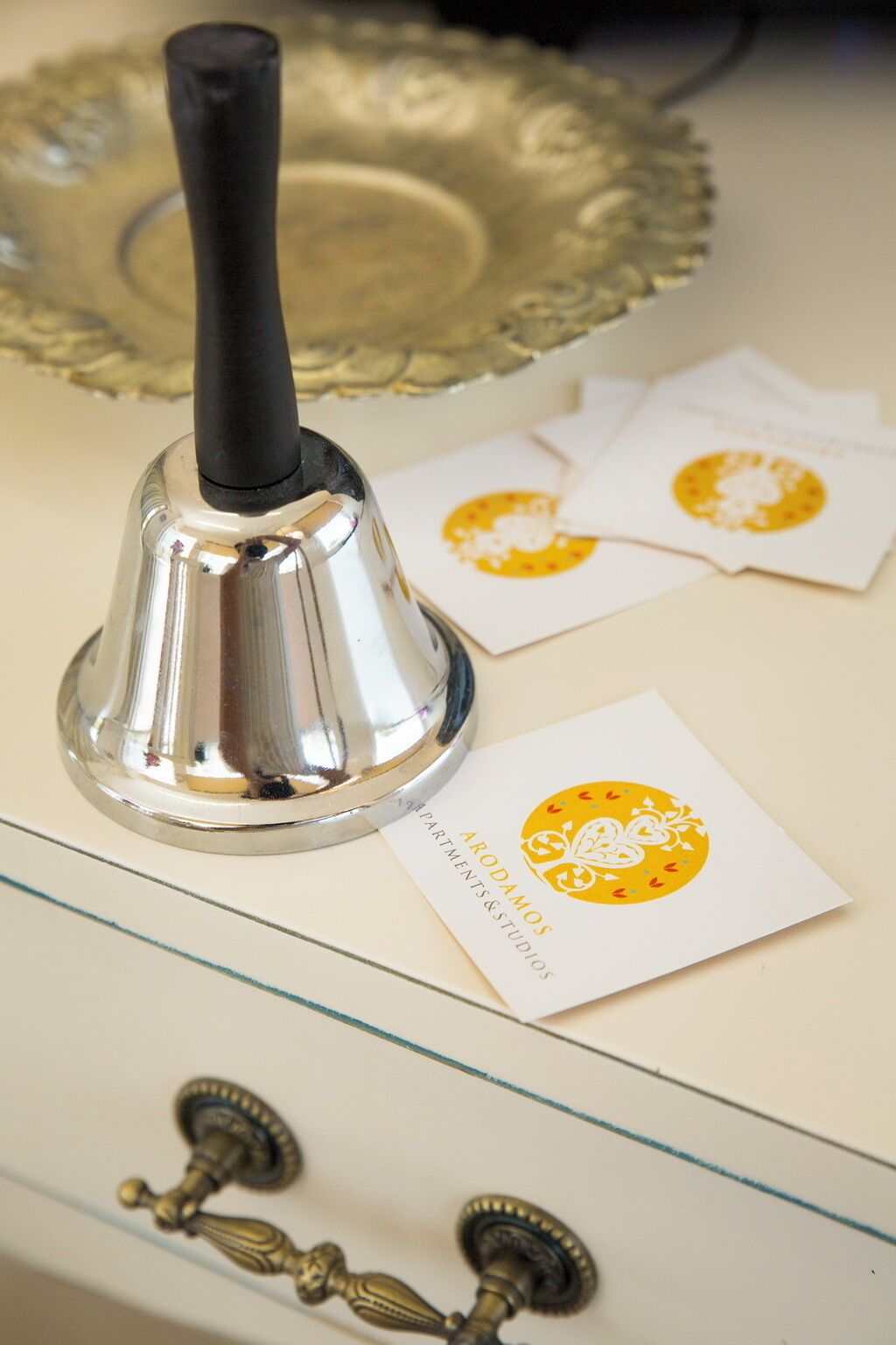 A metallic bell, a glass door with a brass handle, and a white card with a yellow emblem.