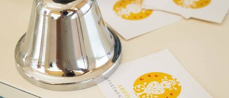 A metallic bell, a glass door with a brass handle, and a white card with a yellow emblem.