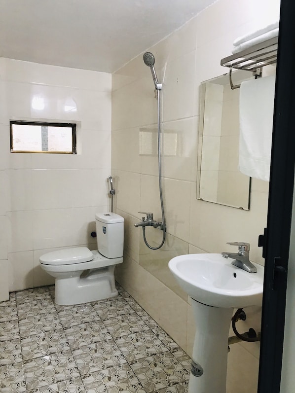 A small, clean bathroom with a toilet, sink, and shower.