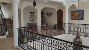 A spacious interior with a balcony, a staircase, and a clock on the wall. - Riyad Azul between nature and the ocean (Sidi Kaouki)