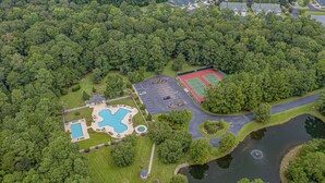 An aerial view of a property with a swimming pool, tennis court, and a lake. - 2 Bed 2Bath 1st Floor Golf and Beach Condo (Pawleys Island)
