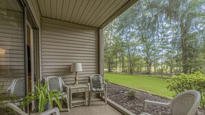 A covered porch with outdoor seating, a lamp, and a view of a grassy area and trees. - 2 Bed 2Bath 1st Floor Golf and Beach Condo (Pawleys Island)
