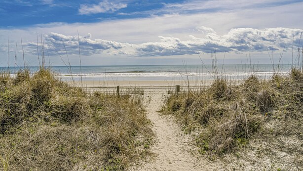 A sandy beach path leading to the ocean with a wooden fence and sparse vegetation. - 2 Bed 2Bath 1st Floor Golf and Beach Condo (Pawleys Island)