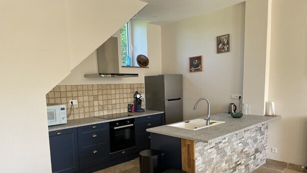 A compact kitchen with a built-in dishwasher, a microwave, a stainless steel refrigerator, a granite countertop, and a stone backsplash.