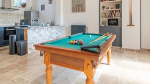 A pool table in a modern kitchen with a built-in bar and a bookshelf.