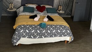 A modern bedroom with a large bed, a heart-shaped pillow, and a unique wall design.