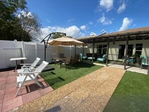 A backyard with a patio area, outdoor seating, and a covered section.