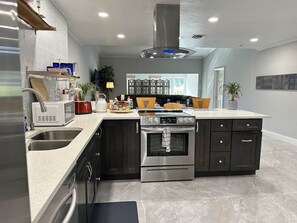 A modern kitchen with a stainless steel range, double sink, and dark cabinetry.