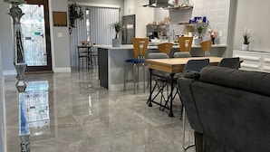 A modern kitchen with a central island, a dining area with a wooden table and chairs, and a living area with a sofa and a coffee table. - Florida Vacation Villa with hot tub (Fort Lauderdale)