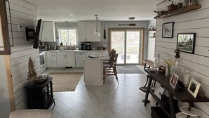 A spacious kitchen with a central island, a dining area with a bench, and a living space with a fireplace. - Beaver's Bend Lakefront Retreat ~16 mi to Slopes & Pet Friendly! (Whitingham)
