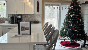 A modern kitchen with a central island, white cabinets, and a decorative Christmas tree. - Beaver's Bend Lakefront Retreat ~16 mi to Slopes & Pet Friendly! (Whitingham)