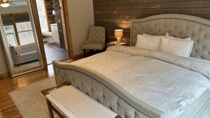 A bedroom with a large bed, a bench, a chair, and a wooden headboard. - Beaver's Bend Lakefront Retreat ~16 mi to Slopes & Pet Friendly! (Whitingham)