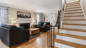 Ein Wohnzimmer mit Kamin, zwei Sofas, einem Couchtisch und einer Treppe.