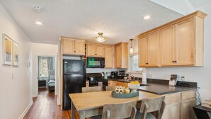 A modern kitchen with wooden cabinets, a black refrigerator, a microwave, and a dining area with a wooden table and chairs. - Newly Renovated Tremont Treasure I Cozy + Modern (Cleveland)