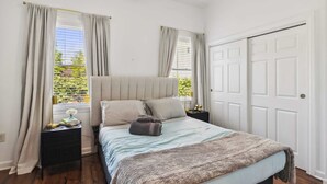 A bedroom with a bed, nightstands, a window with curtains, and a door. - Newly Renovated Tremont Treasure I Cozy + Modern (Cleveland)