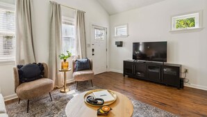A living room with a flat-screen TV, two armchairs, a coffee table with a tray, and a window with curtains. - Newly Renovated Tremont Treasure I Cozy + Modern (Cleveland)