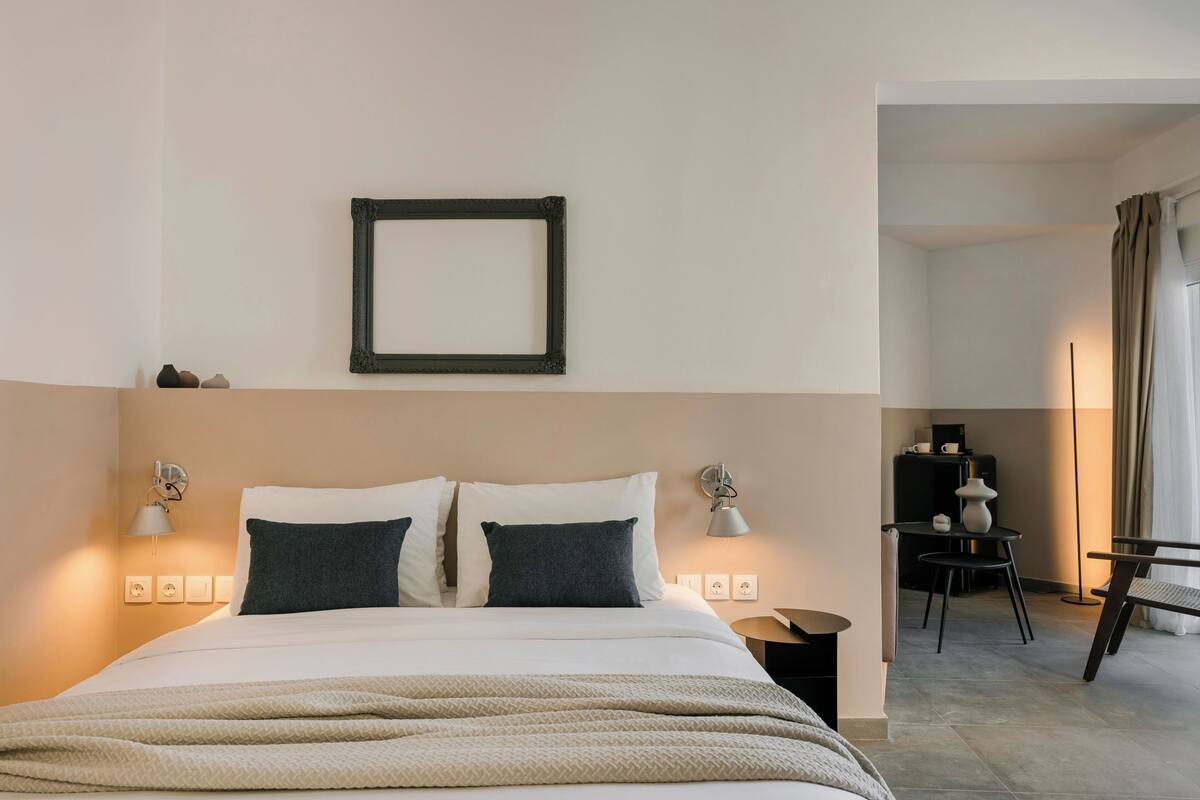 A hotel room with a bed, bedside lamps, a desk, and a chair.