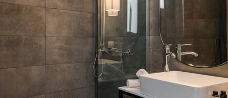 Un baño moderno con cabina de ducha de vidrio, un lavabo blanco y un espejo.