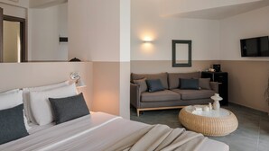 Una camera d'albergo moderna con un letto, una poltrona, un tavolino rotondo e una televisione a schermo piatto.