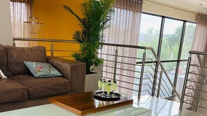 A modern living room with a glass coffee table, a brown sofa, and a potted plant. - On Hill Lodge (Bloemfontein)