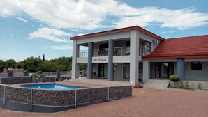 A hotel with a reception area, a swimming pool, and a red-roofed building. - On Hill Lodge (Bloemfontein)