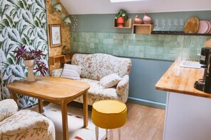 A cozy kitchen with a floral sofa, wooden table, and a yellow ottoman. - Holiday home in the countryside, with pool, garden (Rozewko)