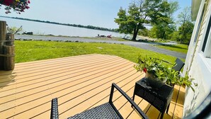 Une terrasse en bois avec vue sur un lac, une chaise et une plante en pot.