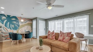 A living room with a beige sofa, a round coffee table, and a ceiling fan.
