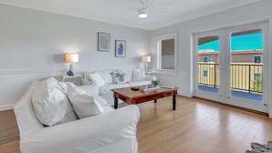 Ein geräumiges Wohnzimmer mit einem weißen Sofa, einem Holztisch und einem Deckenventilator.