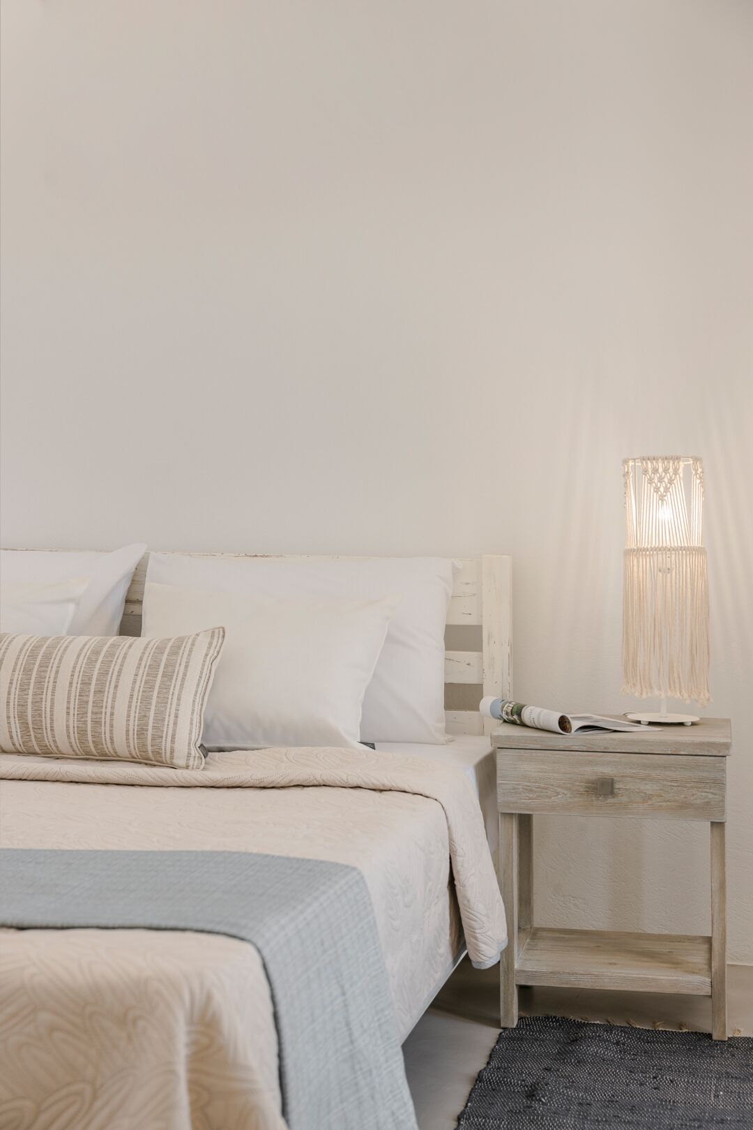 Une chambre à coucher bien rangée, avec un lit, des oreillers, une table de chevet et une lampe.