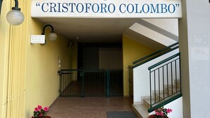 A building entrance with a sign reading "Residence Cristoforo Colombo" and a staircase with a green railing. - App.Mare V&V res.Colombo with swimmingpool+solarium News - Caorle, Veneto, Italy (Caorle)