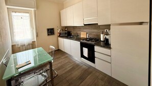 Una cocina moderna con armarios blancos, una mesa de comedor de vidrio y un horno empotrado.