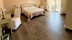 Un dormitorio con cama, una silla, un escritorio y una ventana con cortinas.