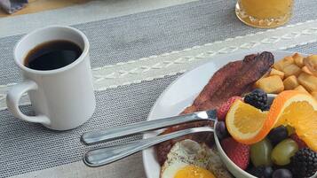 A breakfast setting with eggs, bacon, toast, and fruit on a table.