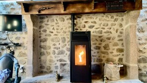 Ein Kamin aus Stein mit einem modernen Holzofen, einem angebrachten Fernseher und einer Steinwand.
