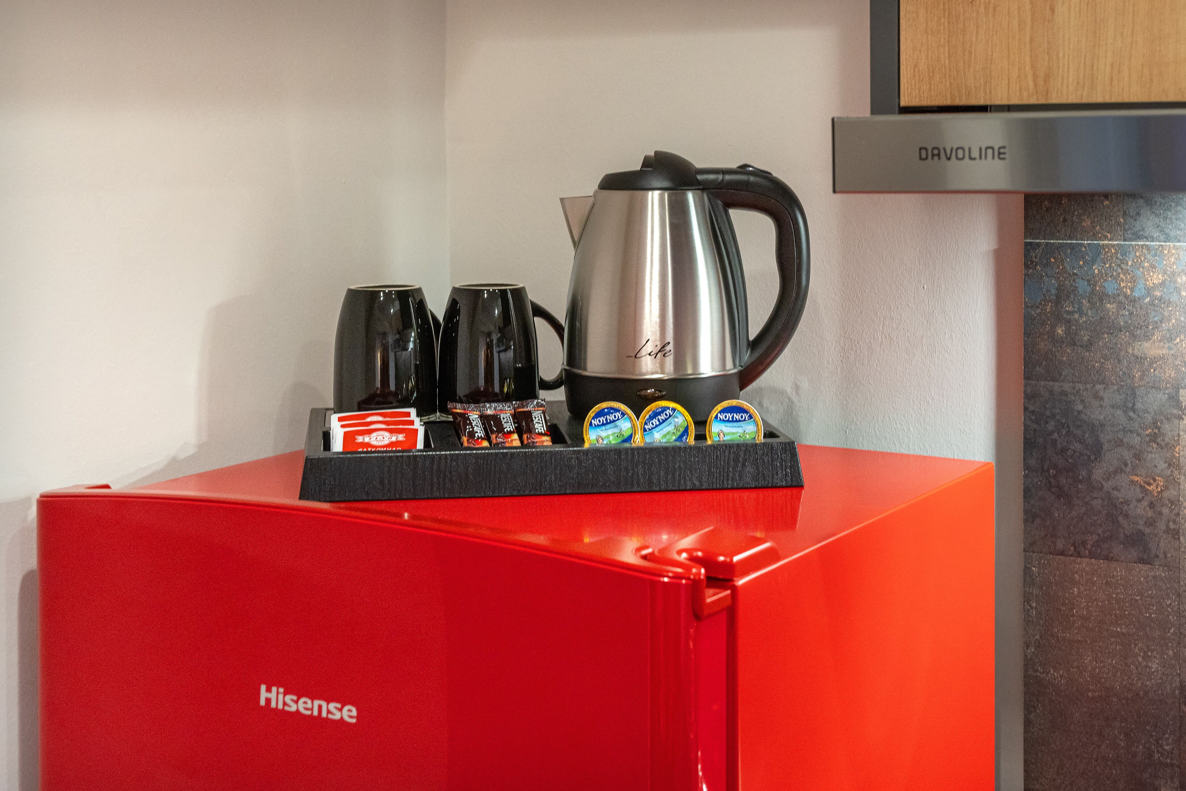 A red Hisense appliance with a coffee maker and tea pots on top.