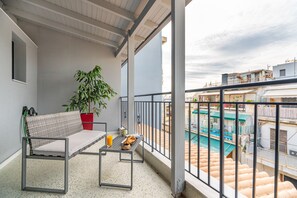 Un balcon avec un canapé, une table sur laquelle se trouve un plateau avec de la nourriture et une boisson, et une plante en pot.