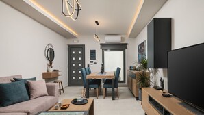 Una sala de estar moderna con sofá, mesa de centro, televisor, comedor y cocina.